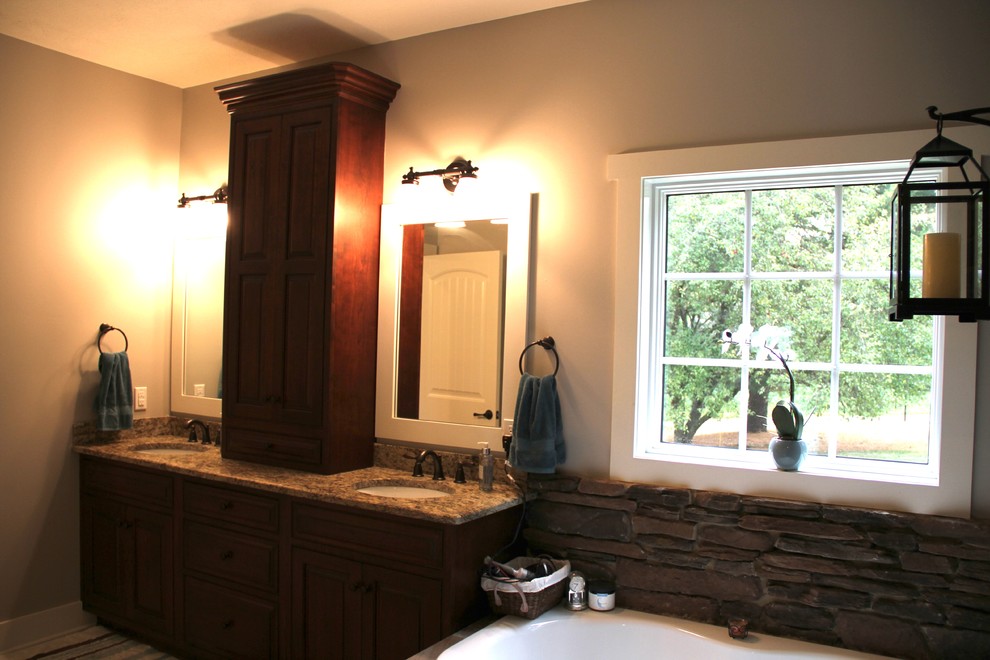 Large mountain style master gray tile and ceramic tile ceramic tile corner bathtub photo with recessed-panel cabinets, dark wood cabinets, a one-piece toilet, gray walls, an undermount sink and granite countertops
