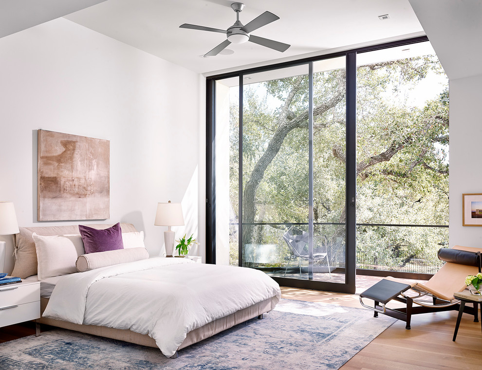 Contemporary bedroom in Austin with white walls and medium hardwood floors.