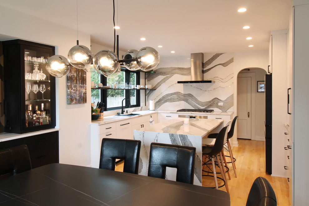Inspiration for a mid-sized contemporary u-shaped eat-in kitchen in Milwaukee with an undermount sink, flat-panel cabinets, white cabinets, quartz benchtops, white splashback, engineered quartz splashback, stainless steel appliances, medium hardwood floors, with island and white benchtop.