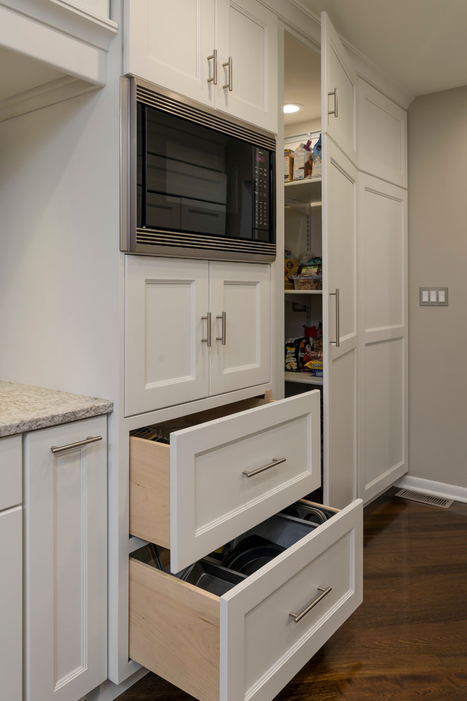 Inspiration for a mid-sized transitional galley medium tone wood floor home design remodel in Chicago with an undermount sink, flat-panel cabinets, white cabinets, quartz countertops, beige backsplash, glass tile backsplash, paneled appliances and a peninsula