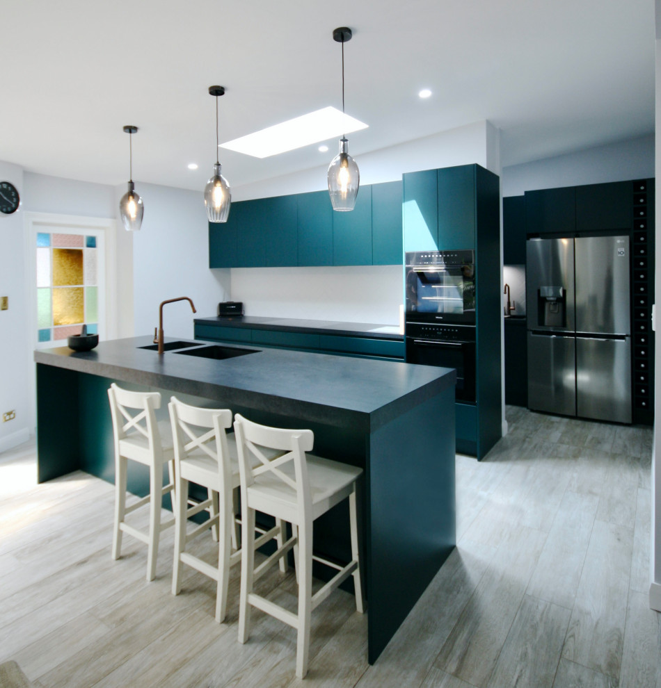 Design ideas for a large urban open plan kitchen in Sydney with a submerged sink, flat-panel cabinets, green cabinets, engineered stone countertops, white splashback, metro tiled splashback, black appliances, medium hardwood flooring, an island, brown floors, black worktops and a coffered ceiling.