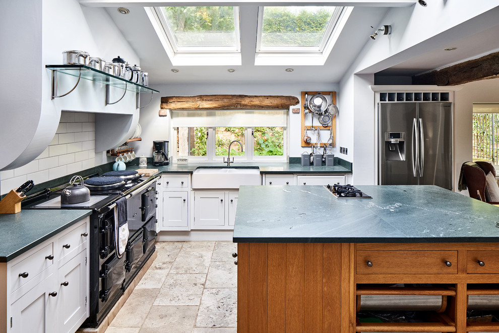 This is an example of a country l-shaped open plan kitchen in Cheshire with a farmhouse sink, shaker cabinets, white cabinets, white splashback, subway tile splashback, stainless steel appliances, with island, beige floor and green benchtop.