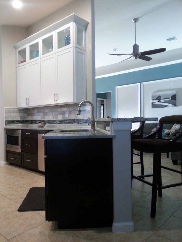 Example of a small transitional galley ceramic tile eat-in kitchen design in Orlando with shaker cabinets, white cabinets, quartzite countertops, gray backsplash, stone tile backsplash, stainless steel appliances and a peninsula
