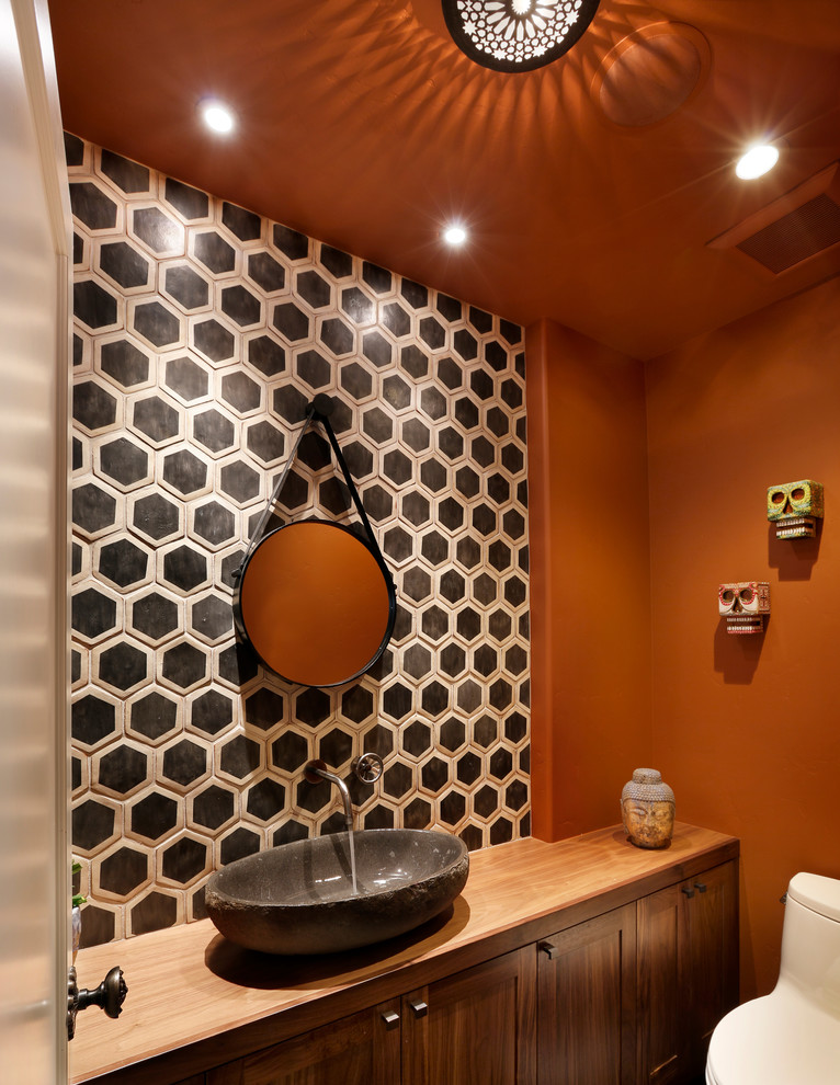 Small eclectic powder room in San Francisco with a vessel sink, shaker cabinets, wood benchtops, ceramic tile, orange walls, black and white tile, dark wood cabinets, a one-piece toilet and brown benchtops.