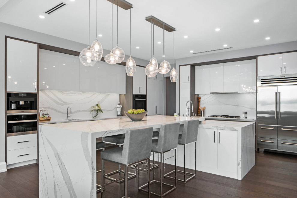 Design ideas for a large contemporary l-shaped open plan kitchen in Tampa with an undermount sink, flat-panel cabinets, white cabinets, quartz benchtops, white splashback, engineered quartz splashback, stainless steel appliances, dark hardwood floors, with island, brown floor and white benchtop.