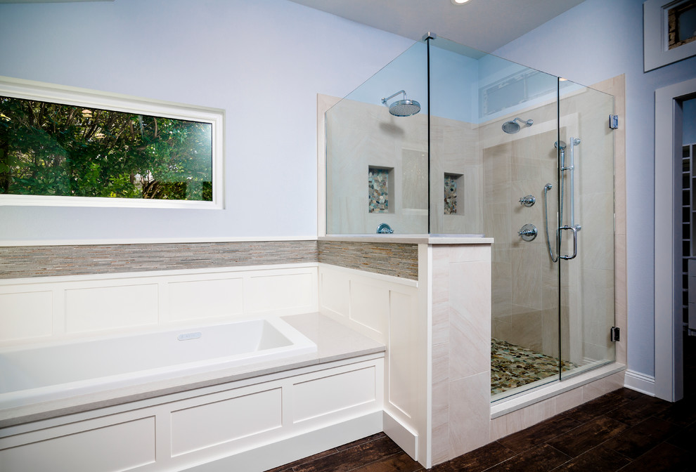 Large transitional master beige tile and porcelain tile porcelain tile and brown floor drop-in bathtub photo with shaker cabinets, white cabinets, a one-piece toilet, blue walls, an undermount sink, quartz countertops and a hinged shower door