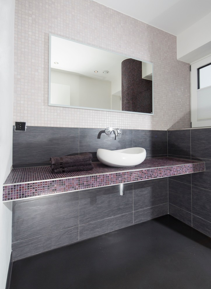 Inspiration for a small contemporary powder room in Dortmund with a vessel sink, tile benchtops, a two-piece toilet, mosaic tile, white walls, multi-coloured tile and purple benchtops.