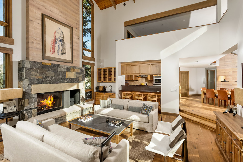 Inspiration for a mid-sized rustic formal and open concept medium tone wood floor living room remodel in Denver with white walls, a standard fireplace, a stone fireplace and no tv
