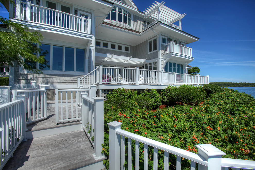 Large beach style three-storey grey exterior in Orange County with wood siding and a hip roof.