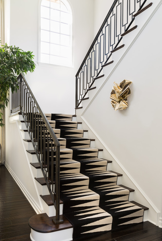 Photo of a transitional wood staircase in Los Angeles with painted wood risers and metal railing.