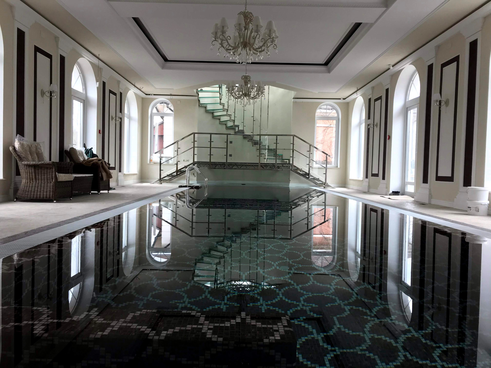 Винтовая стеклянная лестница над бассейном