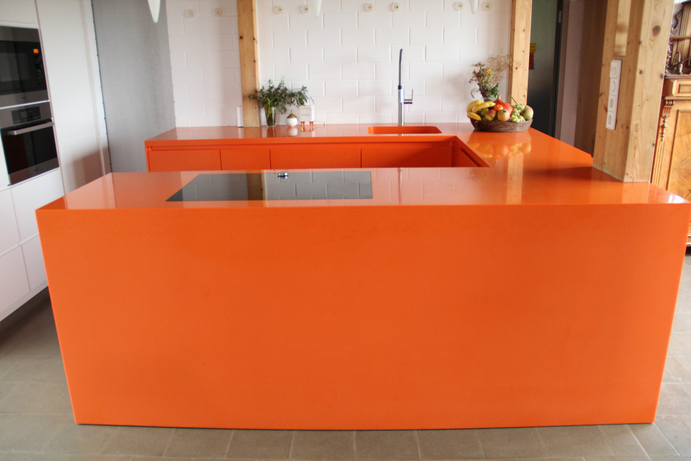 Inspiration for a mid-sized contemporary u-shaped open plan kitchen in Munich with an undermount sink, flat-panel cabinets, orange cabinets, solid surface benchtops, black appliances, grey floor and orange benchtop.