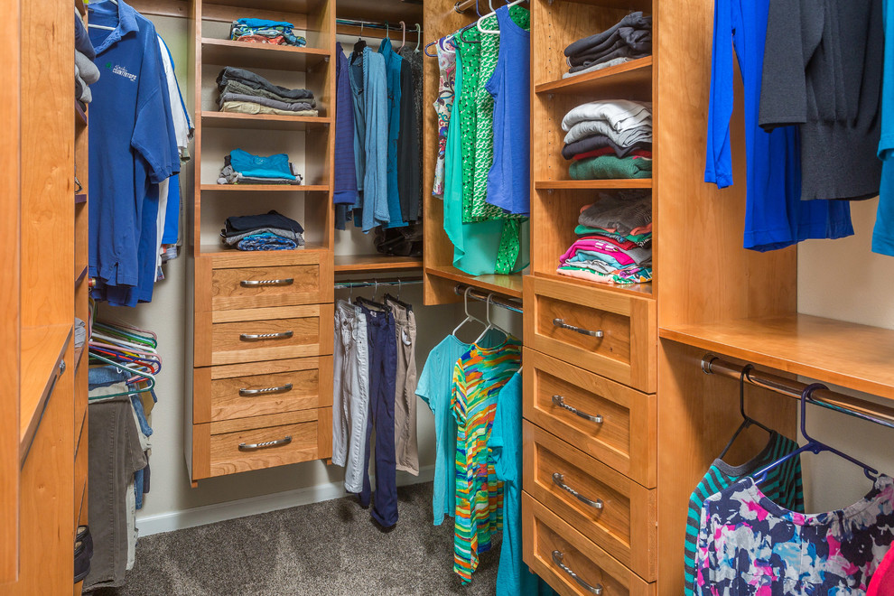 This is an example of a mid-sized traditional gender-neutral walk-in wardrobe in Other with recessed-panel cabinets, medium wood cabinets, carpet and grey floor.