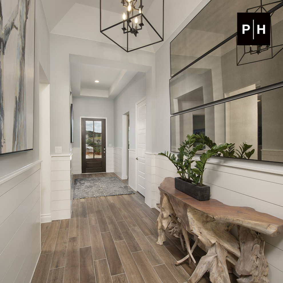 Eingang mit Korridor, grauer Wandfarbe, braunem Holzboden, Einzeltür, dunkler Holzhaustür, gewölbter Decke und Holzdielenwänden in Austin