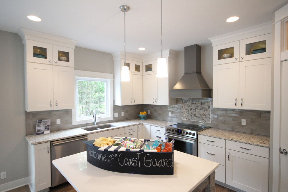 Photo of a beach style u-shaped eat-in kitchen in Grand Rapids with an undermount sink, shaker cabinets, white cabinets, quartz benchtops, grey splashback, subway tile splashback, stainless steel appliances, medium hardwood floors and with island.