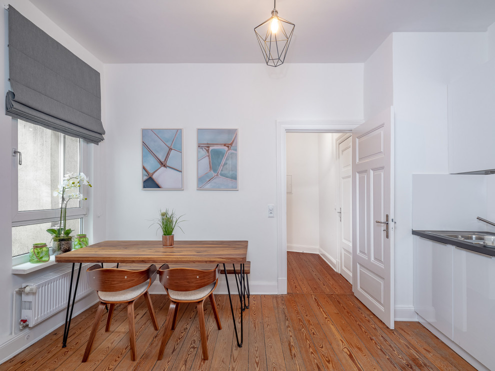 Foto di una piccola sala da pranzo aperta verso la cucina mediterranea con pareti bianche e pavimento in legno verniciato