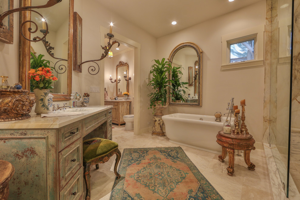 This is an example of a large modern master bathroom in Austin with furniture-like cabinets, distressed cabinets, a freestanding tub, an open shower, white tile, beige tile, gray tile, white walls, marble floors, an undermount sink, marble benchtops, beige floor, marble, an open shower and a two-piece toilet.