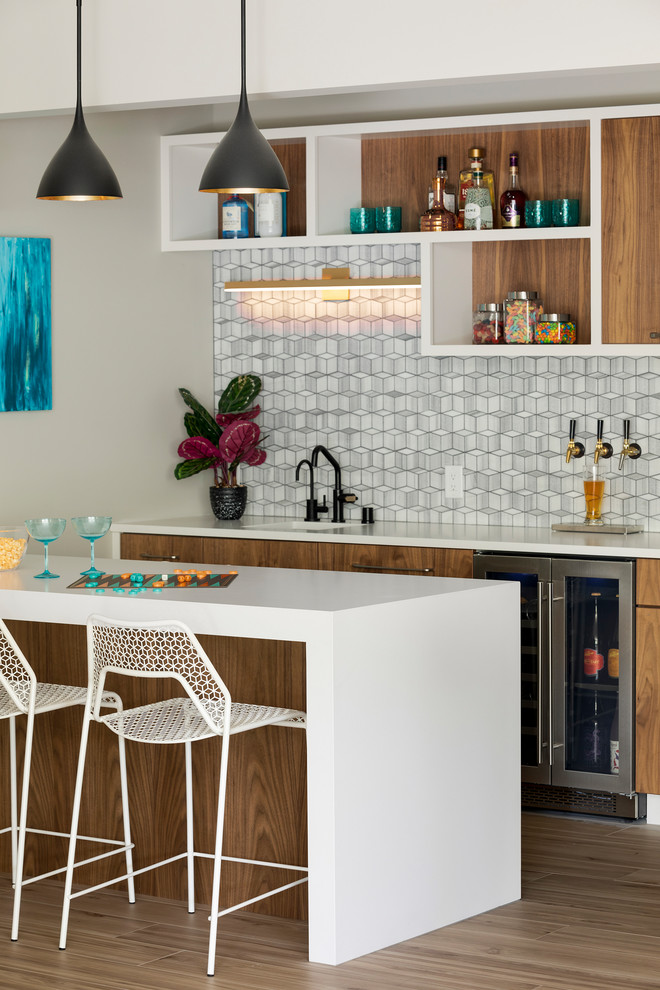 Mid-sized contemporary galley seated home bar in Minneapolis with an undermount sink, quartz benchtops, grey splashback, marble splashback, porcelain floors, white benchtop, open cabinets, white cabinets and brown floor.