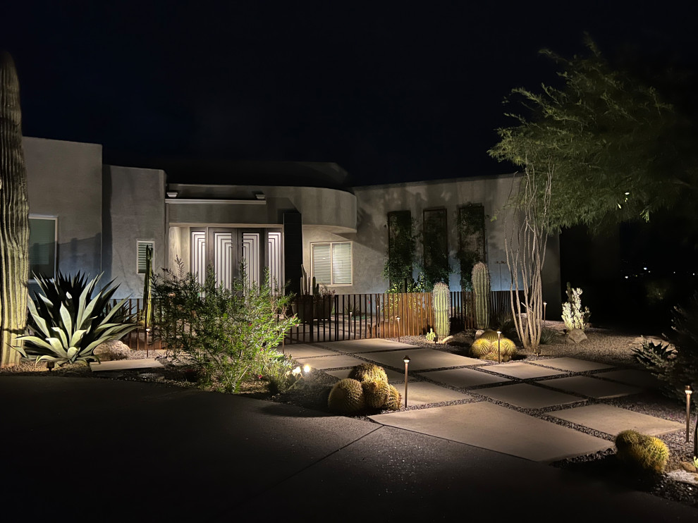 Medium sized front xeriscape full sun garden for winter in Phoenix with a garden path, concrete paving and a metal fence.
