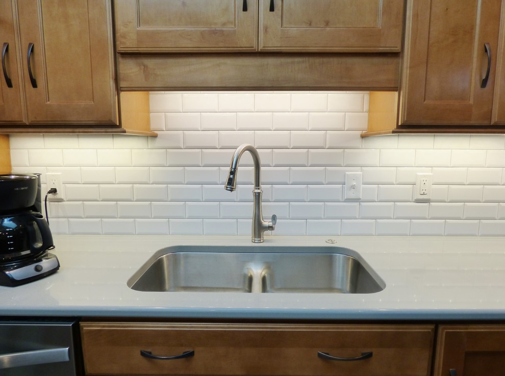 Eat-in kitchen - transitional l-shaped porcelain tile eat-in kitchen idea with an undermount sink, recessed-panel cabinets, medium tone wood cabinets, quartz countertops, white backsplash, subway tile backsplash, stainless steel appliances and an island