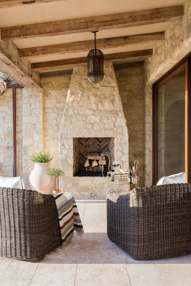 Patio - mid-sized mediterranean backyard stone patio idea in Los Angeles with a fireplace and a roof extension