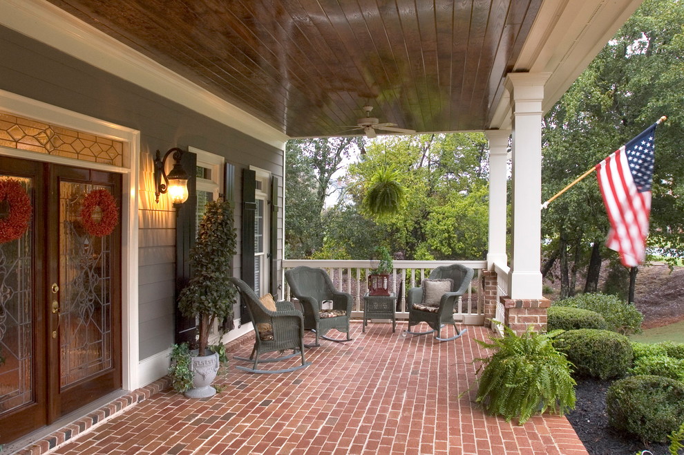 Large traditional front yard verandah in Atlanta with brick pavers and a roof extension.