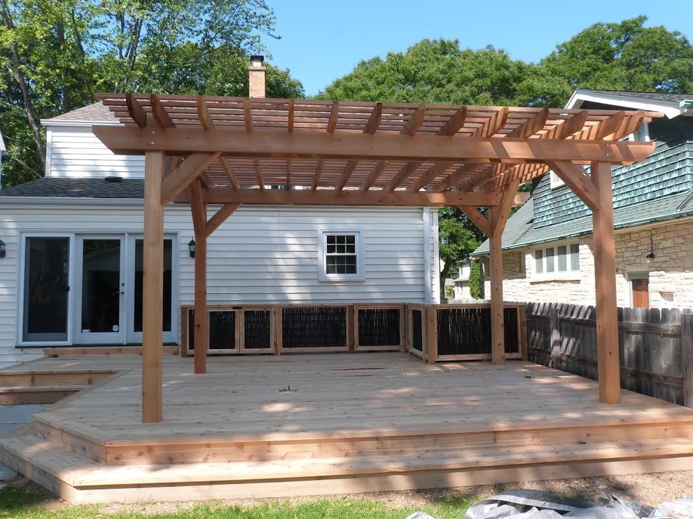This is an example of a mid-sized transitional backyard deck in Milwaukee with a pergola.