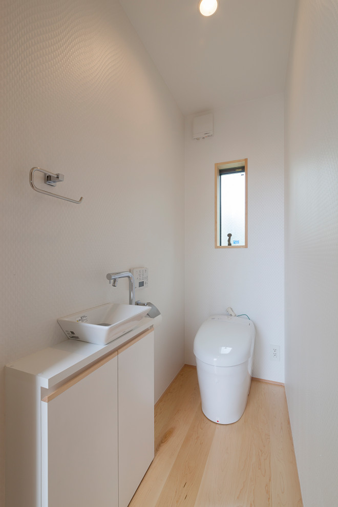 Réalisation d'un WC et toilettes de taille moyenne avec WC à poser, un mur blanc, parquet clair, une vasque, un plan de toilette blanc, un plafond en papier peint et du papier peint.