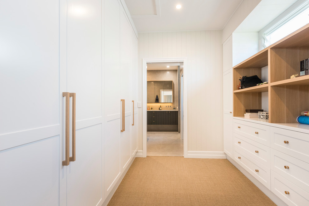 This is an example of a transitional gender-neutral walk-in wardrobe in Brisbane with shaker cabinets, white cabinets, carpet and beige floor.