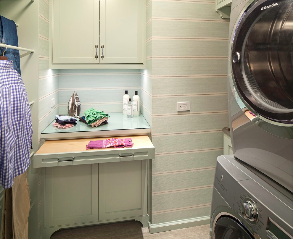 Small transitional dedicated laundry room in New York with an utility sink, green cabinets, glass benchtops, green walls, ceramic floors and a stacked washer and dryer.