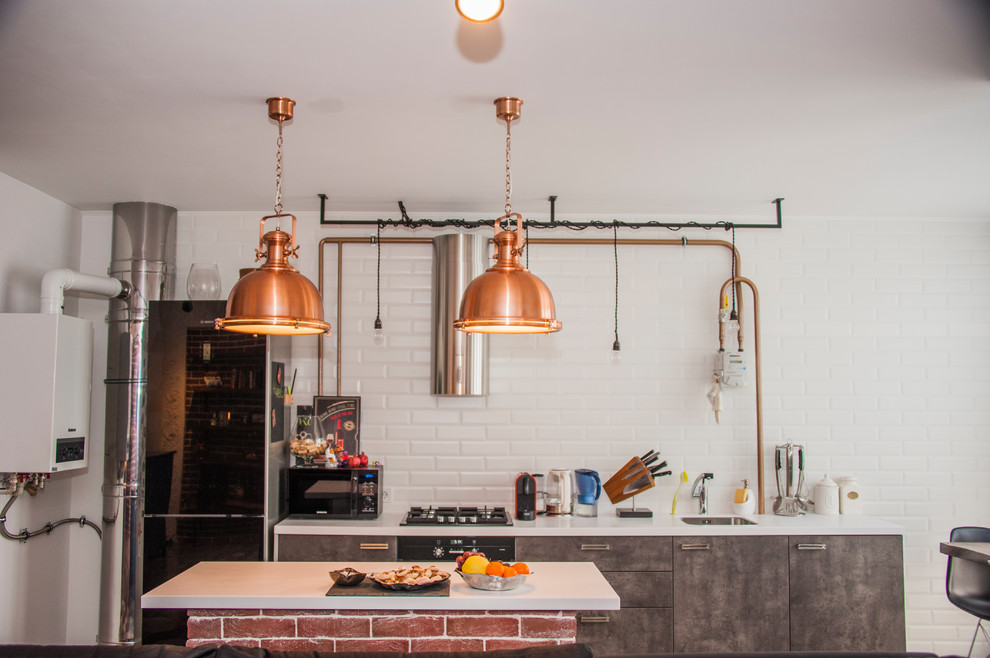 Inspiration for a small industrial single-wall open plan kitchen in Moscow with an undermount sink, flat-panel cabinets, grey cabinets, solid surface benchtops, white splashback, subway tile splashback, black appliances, porcelain floors, with island, grey floor and white benchtop.