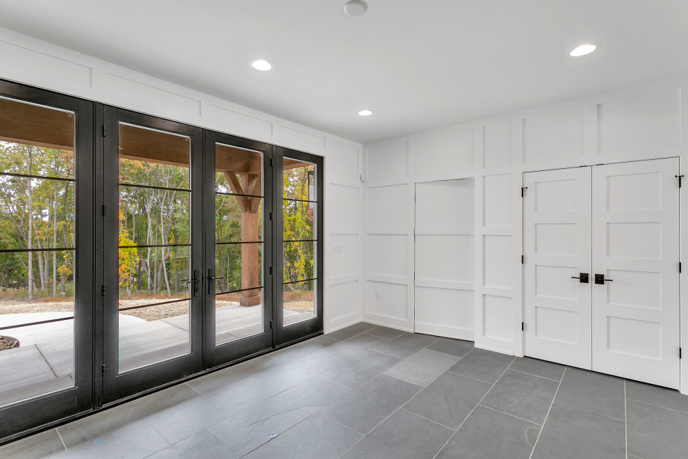 Inspiration for a large rustic slate floor, gray floor and wall paneling foyer remodel with white walls and a black front door