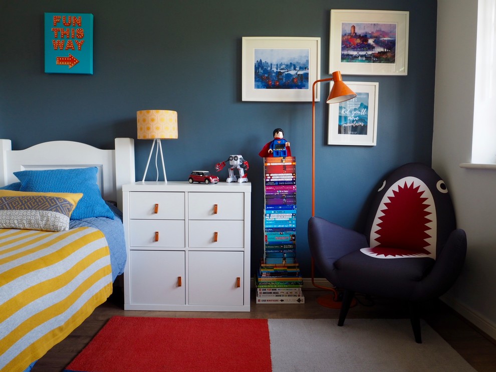 This is an example of a small eclectic kids' bedroom for kids 4-10 years old and boys in Surrey with blue walls, laminate floors and brown floor.