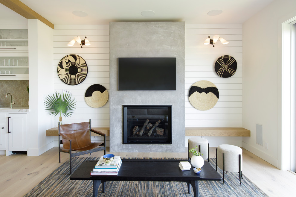 Design ideas for a transitional open concept living room in San Francisco with light hardwood floors, a standard fireplace, a concrete fireplace surround and a wall-mounted tv.