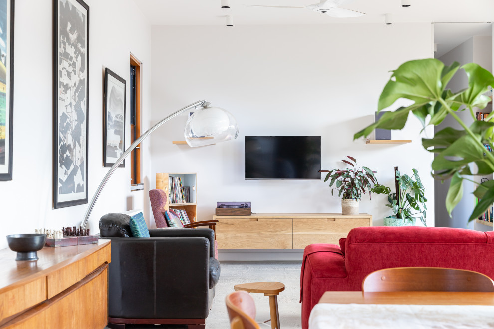 Example of a trendy concrete floor and gray floor living room design in Melbourne with white walls and a wall-mounted tv