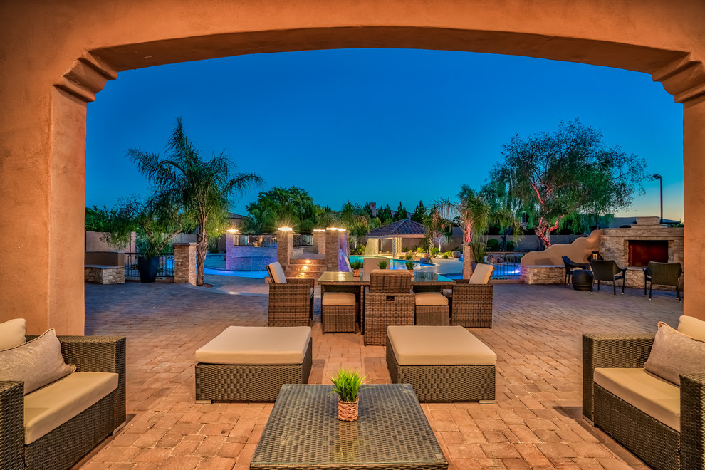 Expansive modern backyard patio in Phoenix with brick pavers and a roof extension.