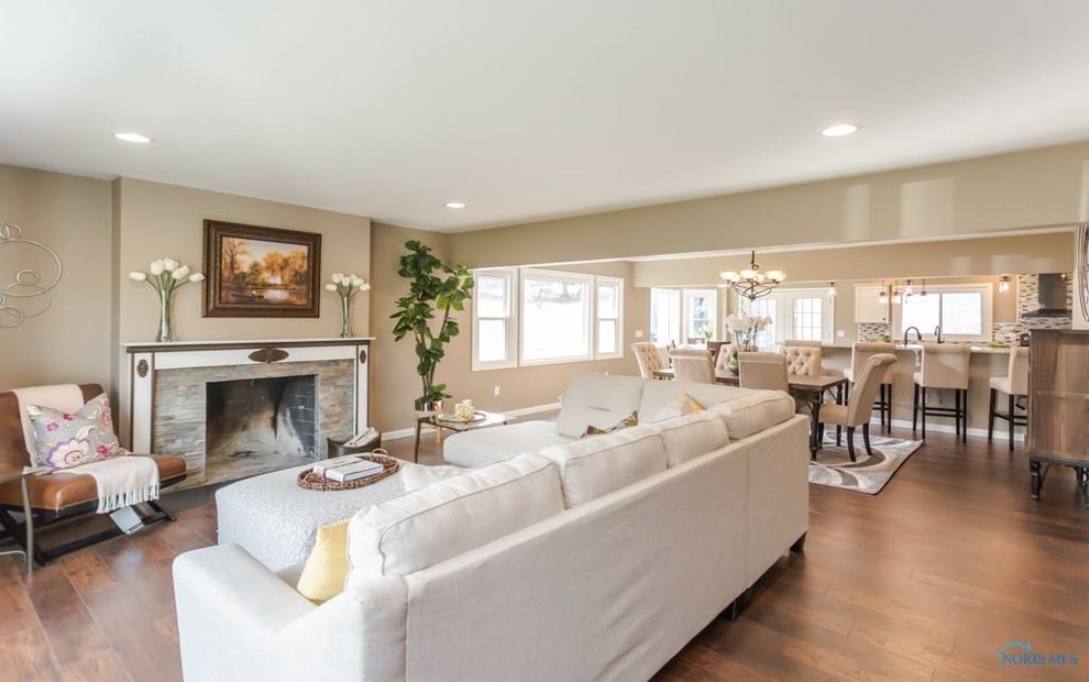 Photo of a large transitional open concept family room in Other with brown walls, medium hardwood floors, a standard fireplace, a stone fireplace surround, a wall-mounted tv and brown floor.
