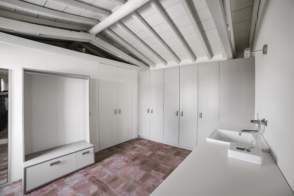 This is an example of a large contemporary dedicated laundry room in Milan with a single-bowl sink, flat-panel cabinets, grey cabinets, quartz benchtops, white walls, brick floors and a side-by-side washer and dryer.