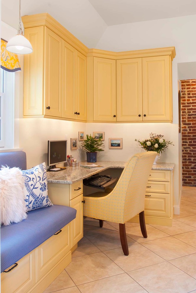 Eat-in kitchen - mid-sized traditional porcelain tile eat-in kitchen idea in Philadelphia with an undermount sink, raised-panel cabinets, yellow cabinets, granite countertops, beige backsplash, porcelain backsplash, paneled appliances and an island