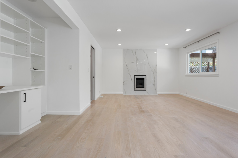 Cette image montre un salon minimaliste de taille moyenne et ouvert avec un mur blanc, un sol en vinyl, une cheminée standard, un manteau de cheminée en pierre, aucun téléviseur et un sol beige.