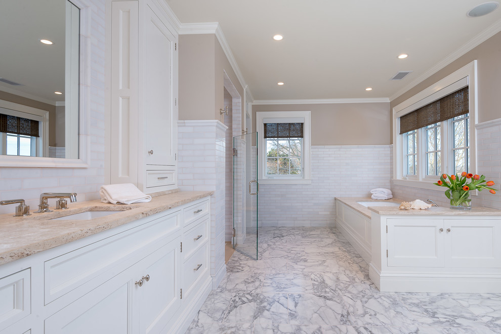 Inspiration for a beach style bathroom in Los Angeles with an undermount sink, white cabinets, an undermount tub, an alcove shower, white tile, stone tile, beige walls, marble floors and furniture-like cabinets.