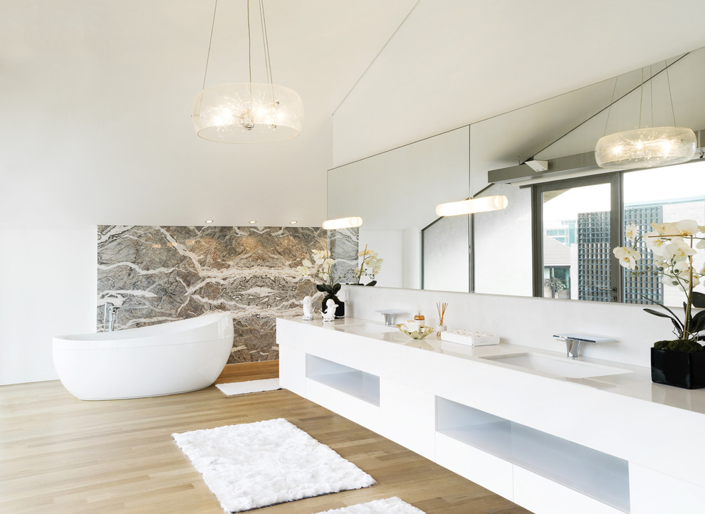 Inspiration for a contemporary bathroom in Singapore with an undermount sink, open cabinets, white cabinets, a freestanding tub, white walls and light hardwood floors.