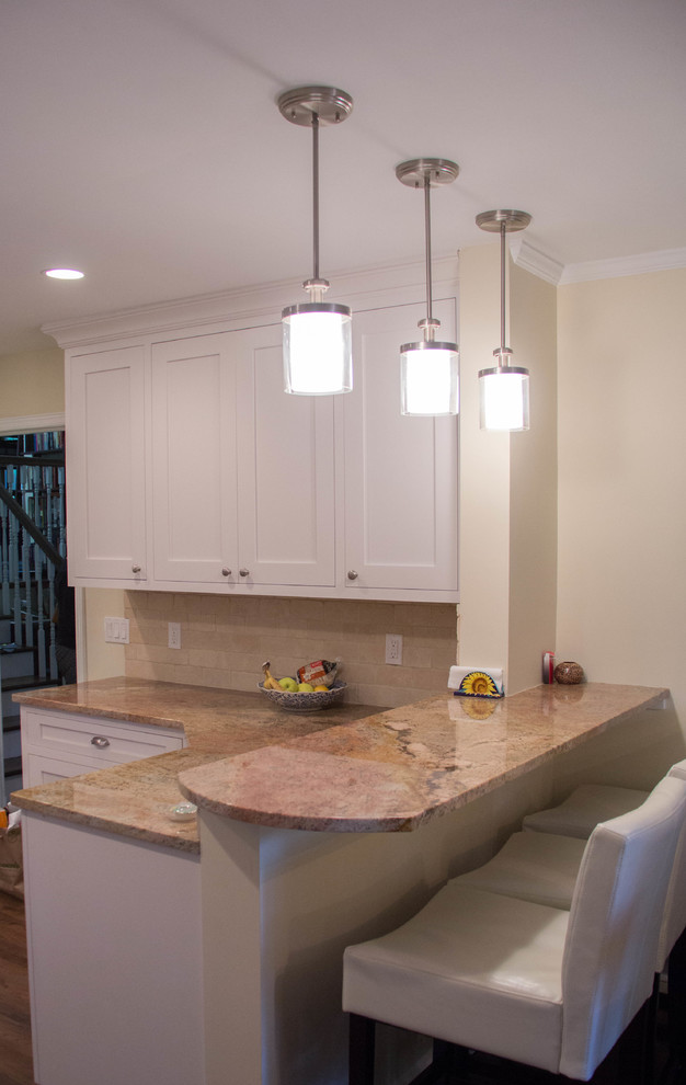 Mid-sized transitional l-shaped eat-in kitchen in New York with a single-bowl sink, recessed-panel cabinets, white cabinets, granite benchtops, beige splashback, stone tile splashback, stainless steel appliances, dark hardwood floors and a peninsula.