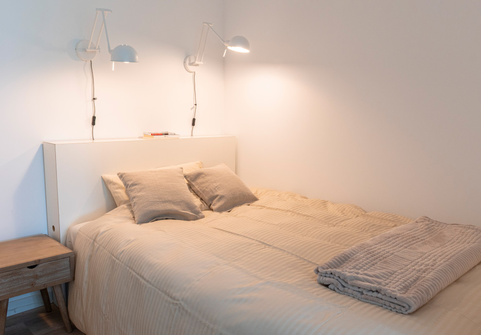 Kleines Modernes Hauptschlafzimmer mit weißer Wandfarbe, Laminat und braunem Boden in Berlin