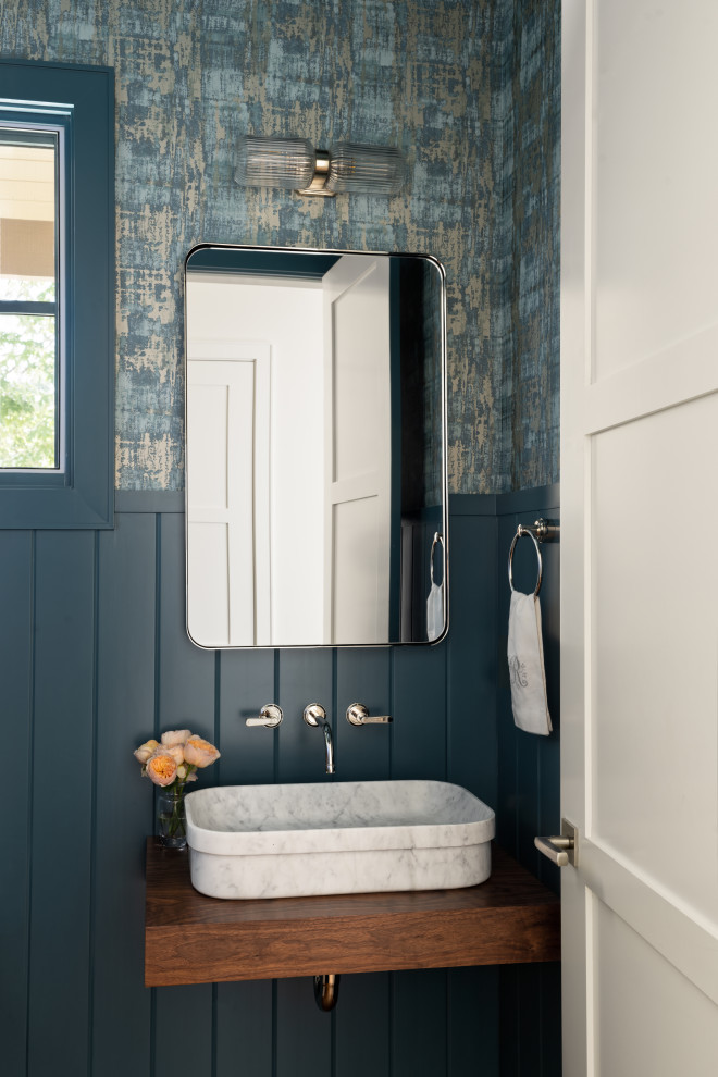 На фото: туалет в стиле неоклассика (современная классика) с синими стенами, настольной раковиной, столешницей из дерева, подвесной тумбой и панелями на части стены с