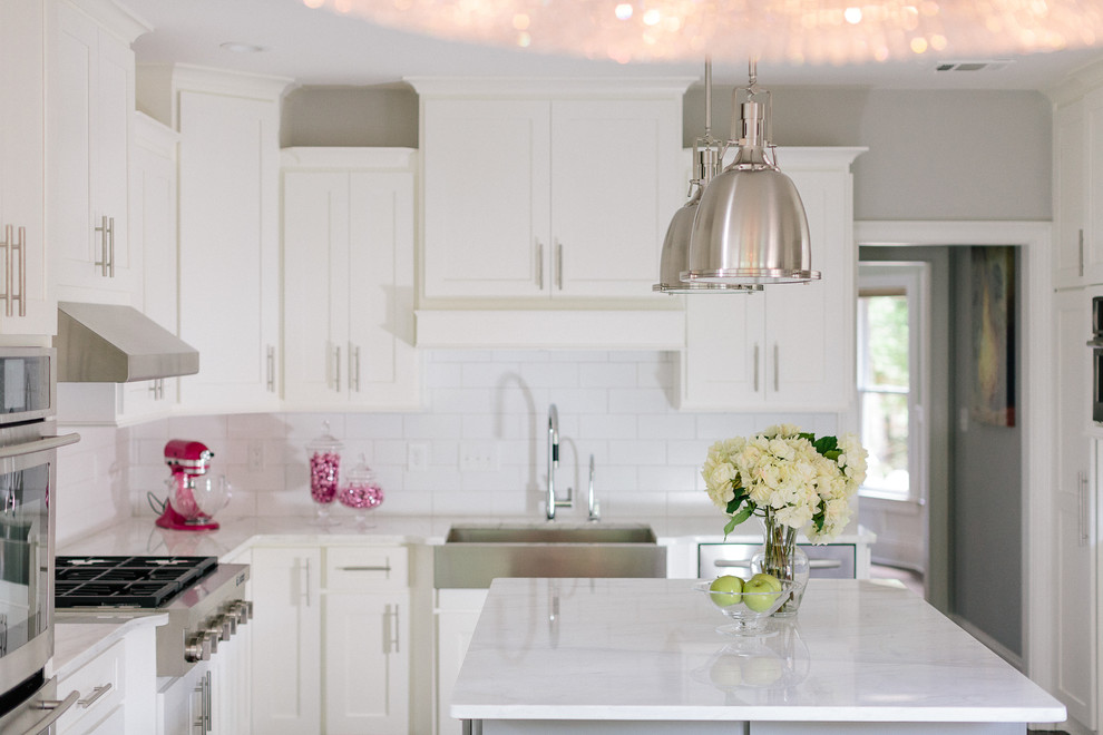Inspiration for a large transitional u-shaped dark wood floor eat-in kitchen remodel in Atlanta with a farmhouse sink, shaker cabinets, white cabinets, marble countertops, white backsplash, ceramic backsplash, stainless steel appliances and an island