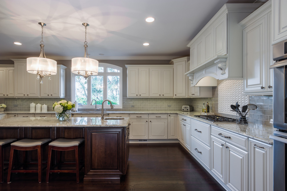 Inspiration for a large transitional u-shaped dark wood floor kitchen remodel in Chicago with a double-bowl sink, raised-panel cabinets, white cabinets, granite countertops, gray backsplash, subway tile backsplash, stainless steel appliances and an island