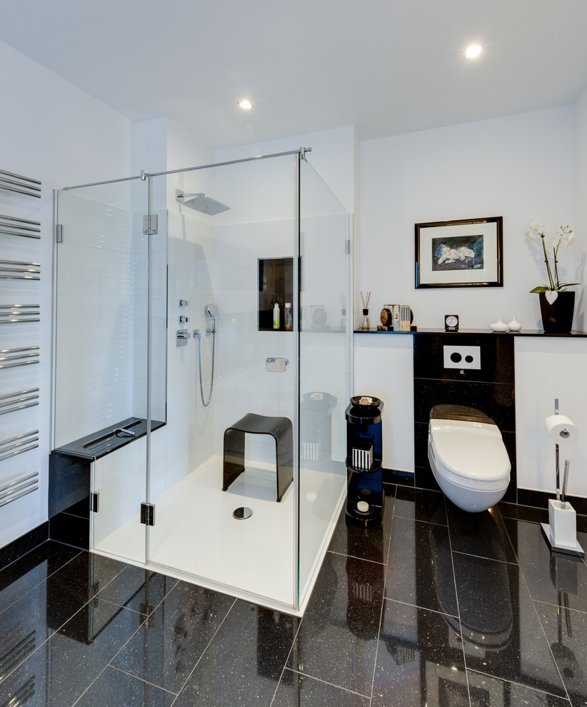 Expansive world-inspired shower room bathroom in Hamburg with flat-panel cabinets, white cabinets, a freestanding bath, a built-in shower, a wall mounted toilet, black and white tiles, ceramic tiles, white walls, ceramic flooring, a trough sink, marble worktops, black floors and a hinged door.