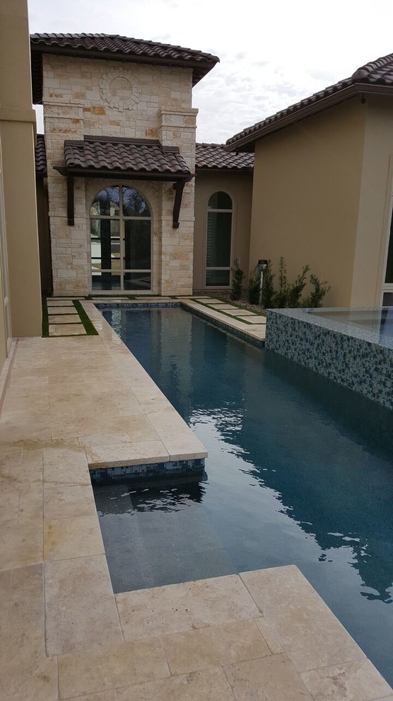 Photo of a large modern backyard rectangular infinity pool in Austin with a hot tub and stamped concrete.