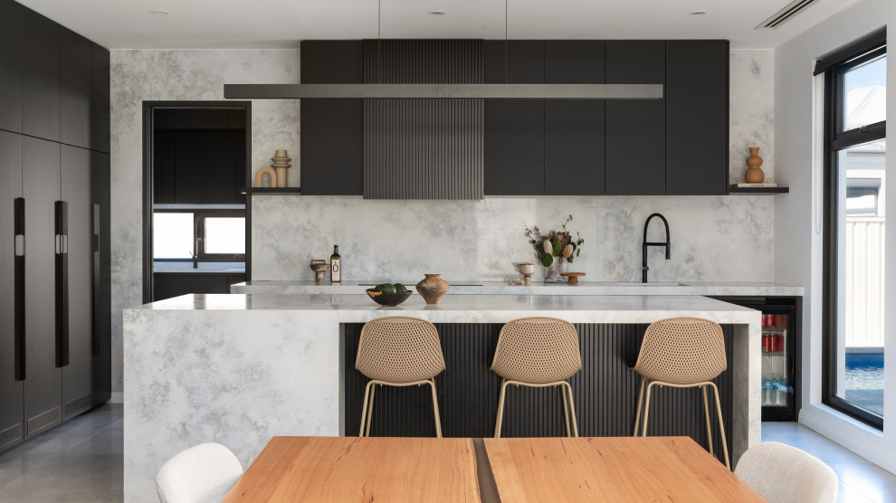 Photo of a contemporary eat-in kitchen in Perth with black cabinets, solid surface benchtops, grey splashback, stone slab splashback, black appliances, with island and grey benchtop.